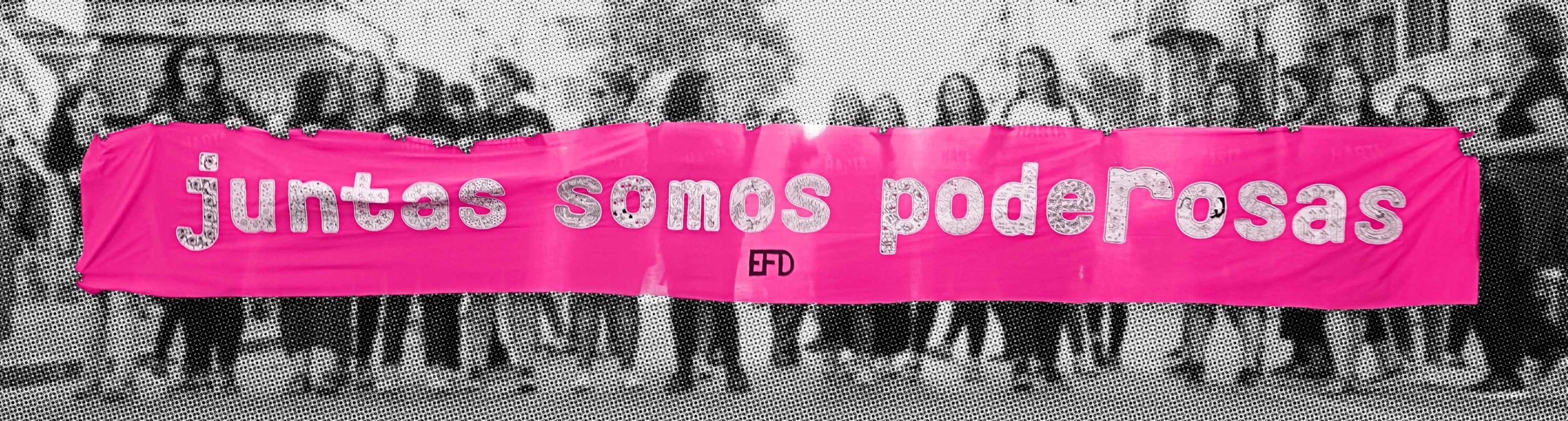 Mujeres sosteniendo una pancarta con letras bordadas "Juntas Somos Poderosas"
